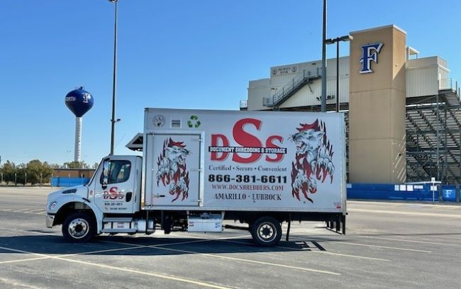 A DSS mobile shredding truck is parked in front of a stadium in Wolfforth, TX