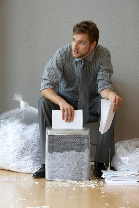 A man uses a small office shredder to protect client data