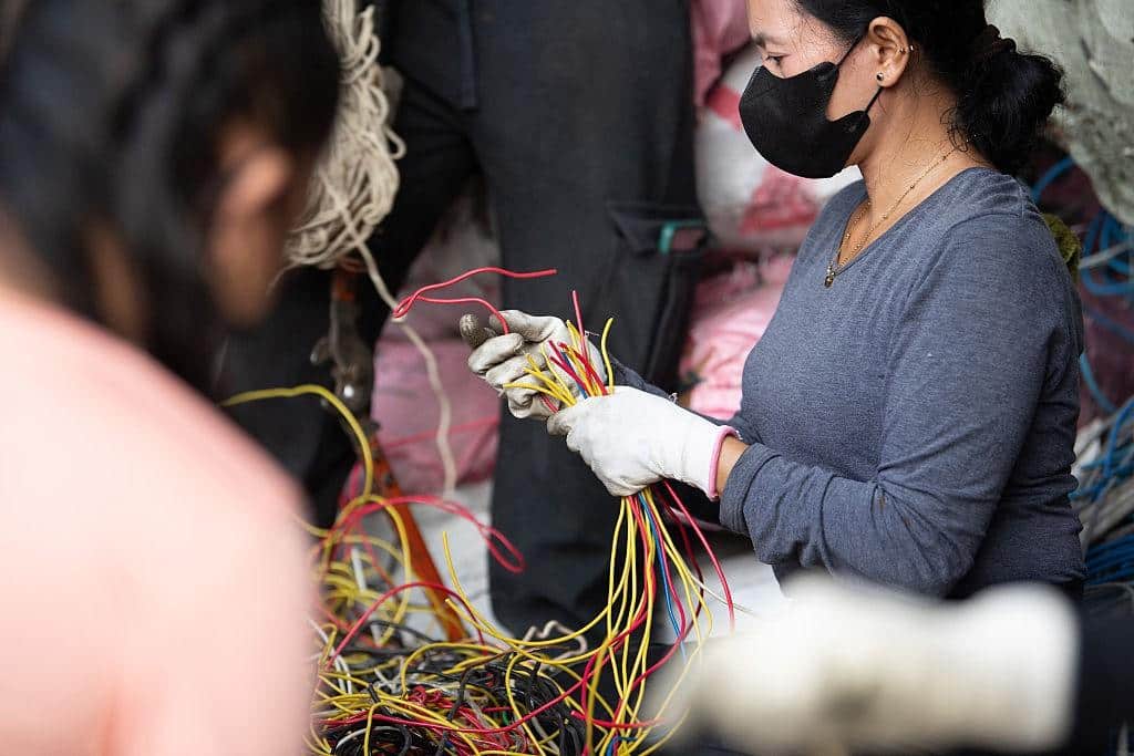 Worker sorting colored wires and electronic components for safe e-waste recycling in Lubbock, TX, to support data security