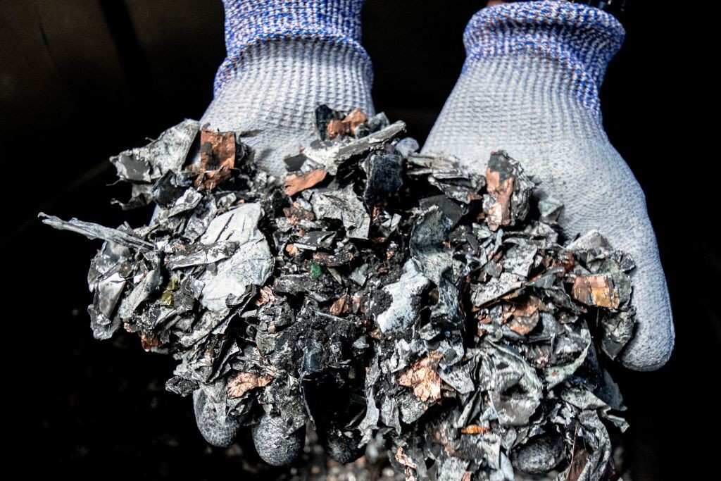 Gloved hands holding shredded electronic components after secure data destruction process in Lubbock, TX